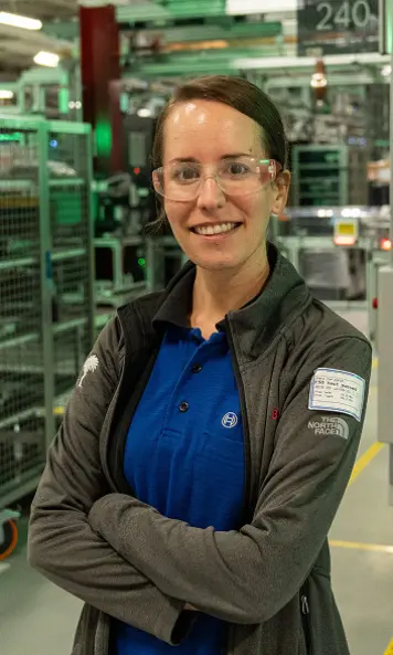 Portrait of a person wearing safety glasses inside a manufacturing facility.