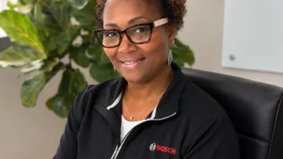 Person wearing glasses and a black Bosch top, seated in an office.