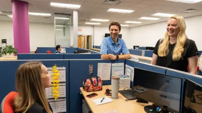 Staff members talking beside desks in an open-plan office.