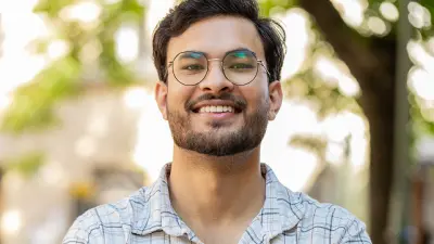 Portrait of a person with glasses and crossed arms outdoors.