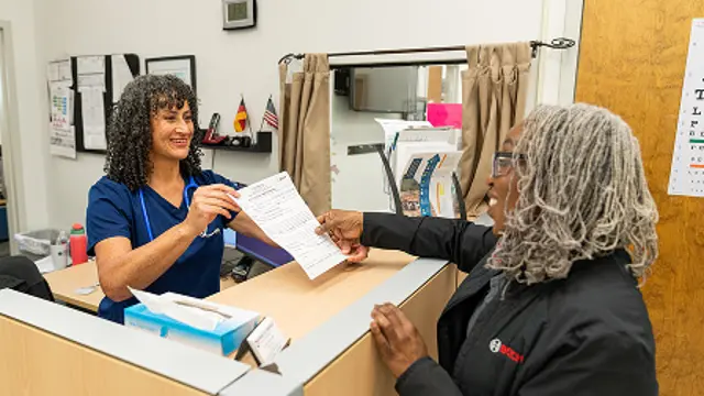 Two people exchanging a document across a service counter.