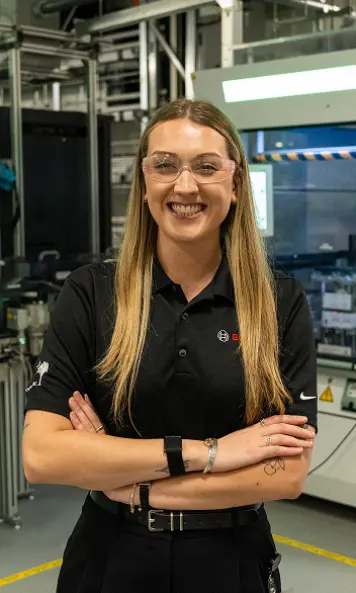 Person wearing safety glasses and a black Bosch shirt in a manufacturing facility.