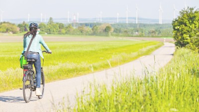 A woman riding a bicycle on the edge of a field